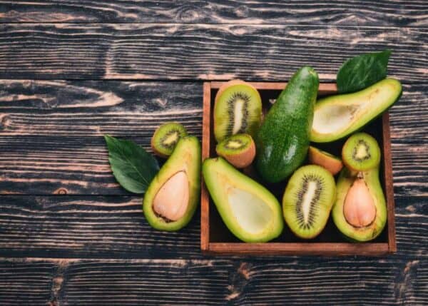 Kiwi and avocado in a wooden basket. On a wooden background. Top view. Free space for your text.