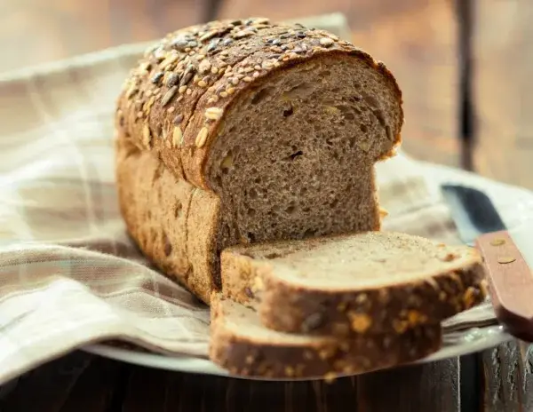 Slices of multigrain bread with visible seeds and grains on a wooden board.