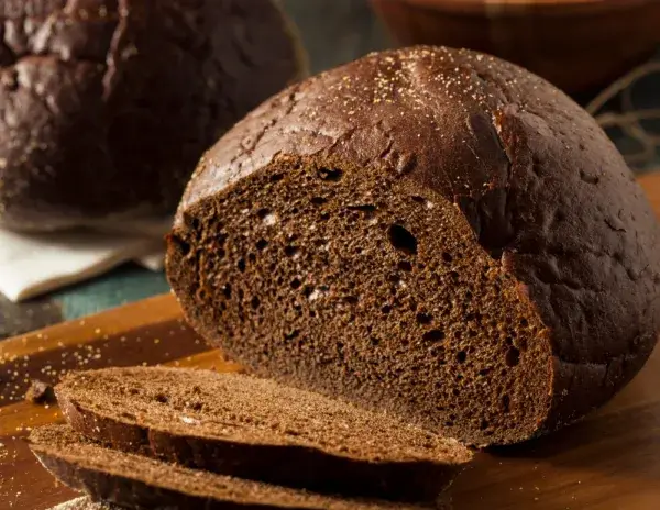 Slices of dark rye bread on a wooden surface, showcasing its dense texture.