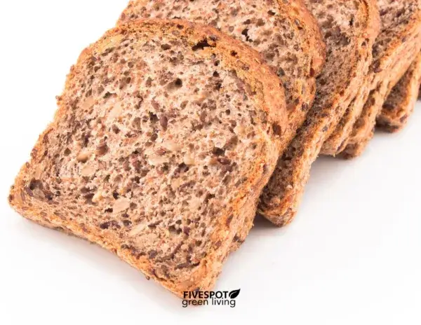 Slices of sprouted grain bread stacked on a cutting board, highlighting its dense texture and nutrient-rich ingredients for a healthy bread choice.